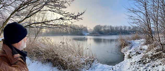 Man is watching the winter lake in the early morning