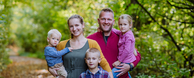 Portrait of happy family with kids in forest.