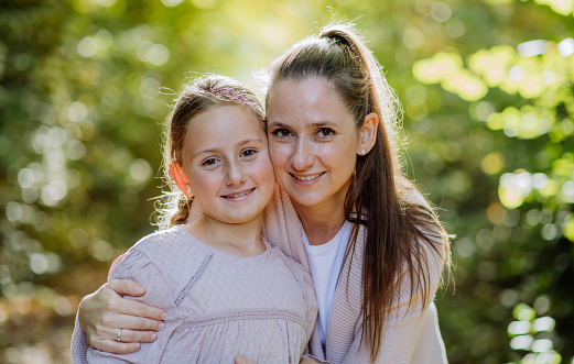 Portrait of mother with her daughter in a forest.