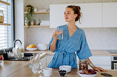 Young woman preparing muesli for breakfast in her kitchen, morning routine and healthy lifestyle concept.