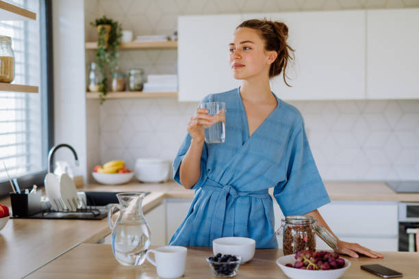 Young woman preparing muesli for breakfast in her kitchen, morning routine and healthy lifestyle concept. stock photo