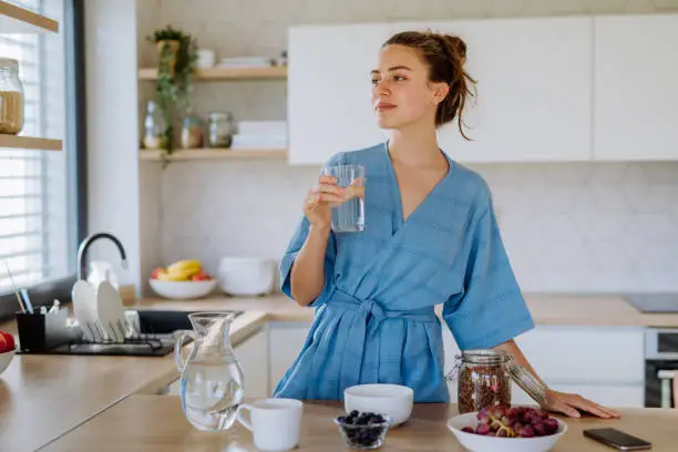Young woman preparing a muesli for breakfast in her kitchen, morning routine and healthy lifestyle concept.