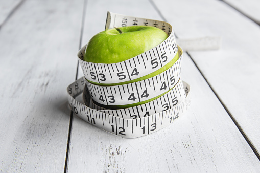 Green apple and tape measure on wood