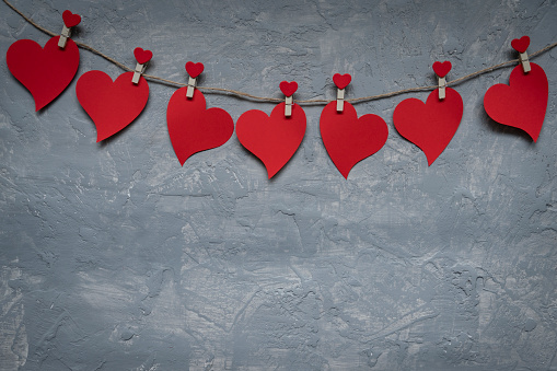 Red hearts on rope with clothespins, on a grey background