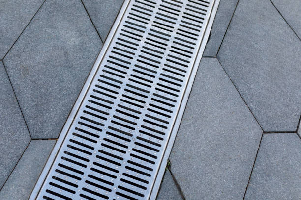 istock Metal storm sewer grate on shaped paving slabs in park. Drainage systems on paving slabs. Sidewalk construct. 1458178249