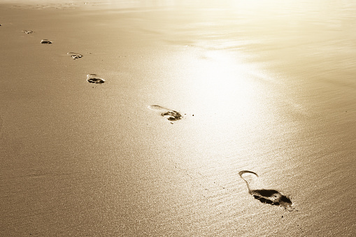 One footprint of human feet on the sand on the beach at sunset, texture abstract background