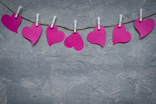 Pink hearts on rope with clothespins, on a grey background