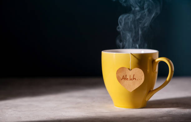 Tea Lover Concept. Eco-Friendly Style Tag made as Heart Shape and Hanging on Cup. Green, Oolong, Fermented, Organic, Healthy and Aromatic Tea. Warm Light shaded the Table stock photo