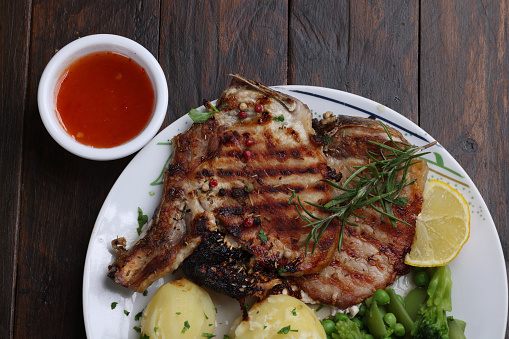 fresh rack of raw pork spare ribs seasoned with spices on black slate tray with paprika, garlic cloves, bay leaves at background, vertical view from above, close-up