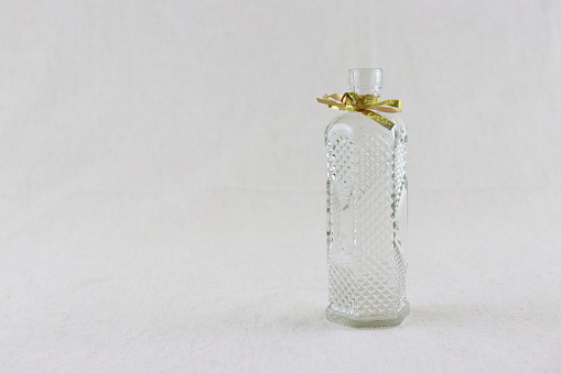 A chic bottle of women's or men's perfume on a glass surface with a pearl gold necklace. Front view pastel background. Empty packaging. presentation