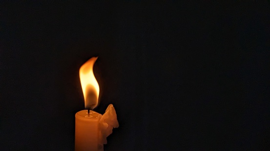 Candle light flame against black background. Concept of memory, remembrance, mourning, grief, and sorrow.