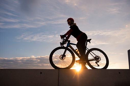 silhouette of woman cycling at sunset