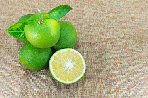 Citrus Fruit, Composition with leaves on brown fabric background