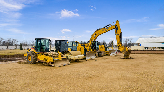 Milwaukee, WI, USA - March 12, 2020: Yellow Caterpillar equipment sitting on a work site. This includes a backhoe loaders, compactor, excavator, and dozer.
