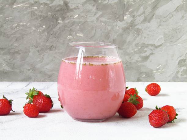 One glass of strawberry juice mixed with milk, on a white and gray background