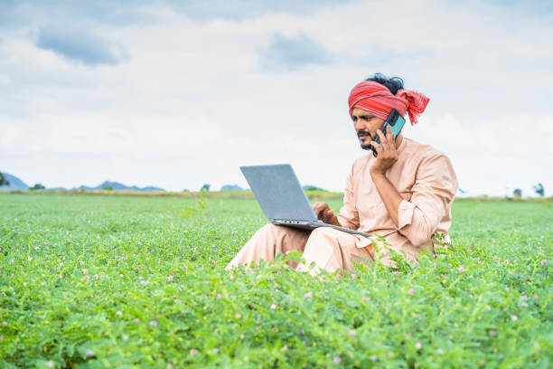 istock Farmer from laptop explaining on mobile phone while sitting on farmland - concept of technology, communication and modern farming 1458192867