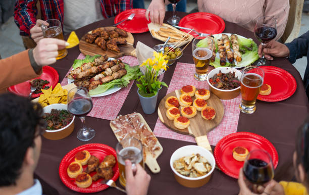 istock A beautifully set table featuring an array of delicious grilled meats, mini pizzas, crispy fries alcoholic beverages. Multiracial group of friends having summer party outdoor 1458194117