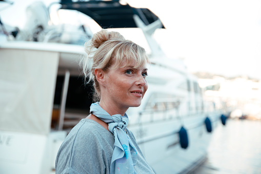 Happy blonde Woman portrait by the ship yacht in the sea marine. Sensual female portrait at sea vacation. Luxury travel lifestyle concept