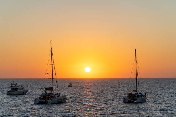 sunset with a round and orange sun in santorini, in the greek islands - moody sky water sport passenger craft scenics imagens e fotografias de stock