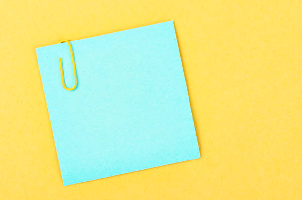 пустая синяя бумага для заметок с скрепкой на желтом фоне для текста или сообщения. - index card paper clip paper blank стоковые фото и изображения