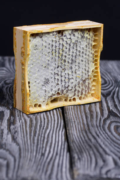 istock Honey in honeycombs in a wooden frame. On black pine boards. On a black background. 1458211637