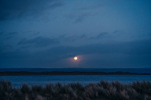A full moon rising above the Devon coast