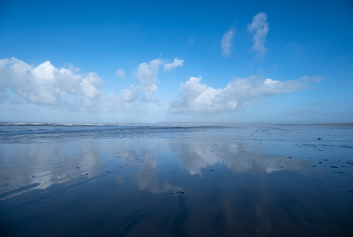 Reflections of sky on a large beach in Devon