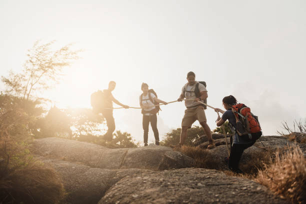 istock Four Asian and female climber groups, Backpacker, helping to pull the rope to support friends to the top of the hill, the concept of outdoor adventure activities. 1458215537