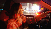 Woman driving a car at night, waiting at a red light