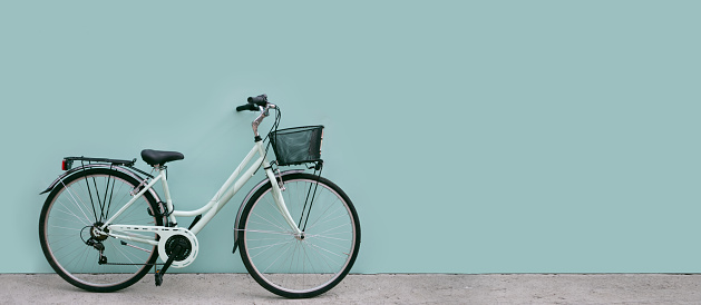 The bicycle stands against the background of a blue wall copy space