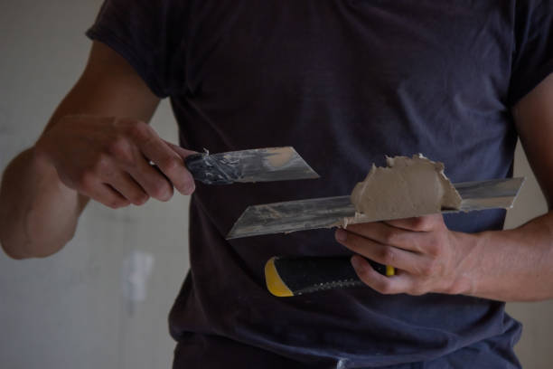 istock A man holds a spatula with putty in his hands. Selective focus. 1458222642