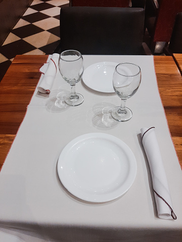 Table setting for dinner: empty plates,  cloth and two glasses. Copy space