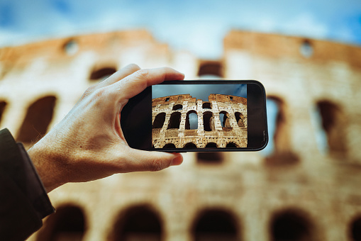 POV photo of a man Photographing the Coliseum of Rome with a mobile phone