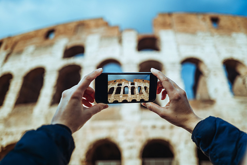 POV photo of a woman Photographing the Coliseum of Rome with a mobile phone