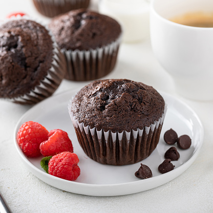 Homemade chocolate muffins with a cup of coffee in a muffin pan freshly baked with chocolate chips