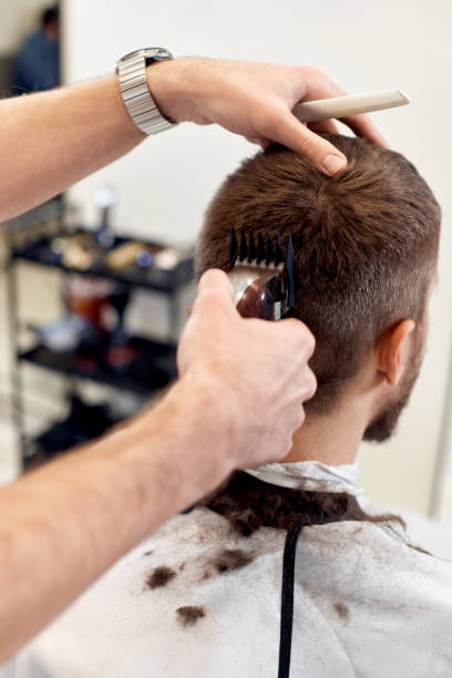 istock Barber trim hair with clipper on handsome bearded man 1458234419