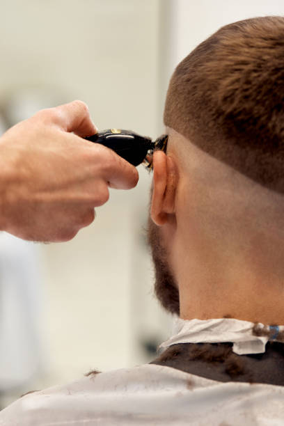 istock Barber trim hair with clipper on handsome bearded man 1458234439