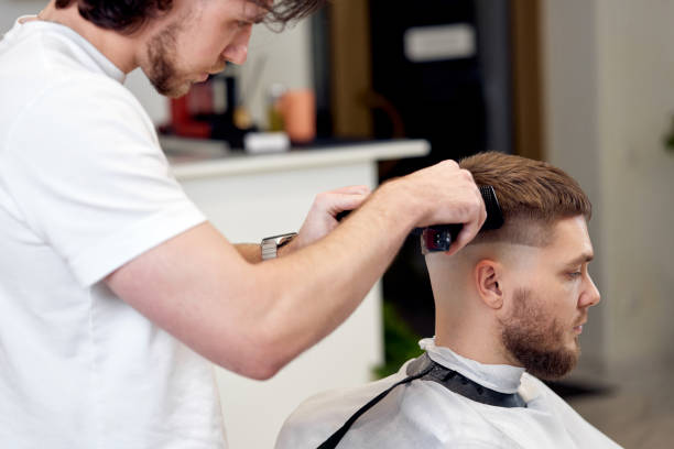 istock Barber trim hair with clipper on handsome bearded man 1458234473