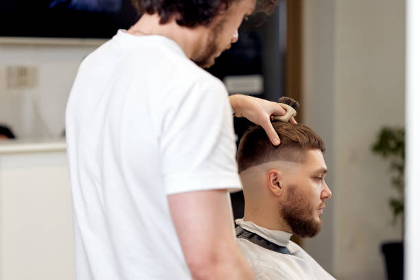 istock Barber trim hair with clipper on handsome bearded man 1458234476