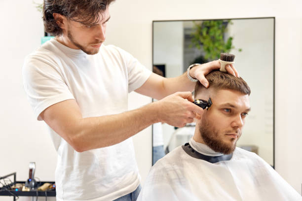istock Barber trim hair with clipper on handsome bearded man 1458234495