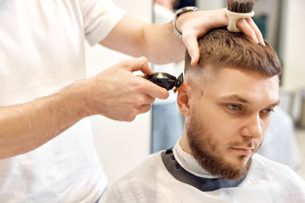 istock Barber trim hair with clipper on handsome bearded man 1458234498