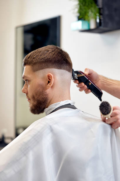 istock Barber trim hair with clipper on handsome bearded man 1458234523