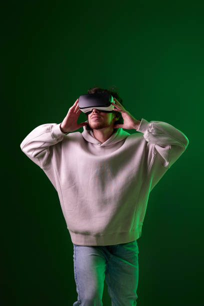 man in vr glasses and sweatshirt plays on blue background.