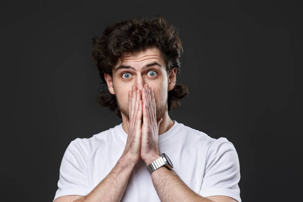 istock frustrated young man on dark gray background. sadness 1458237318