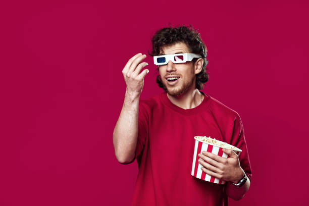 istock handsome bearded man in 3d-glasses, t-shirt showing popcorn 1458237577