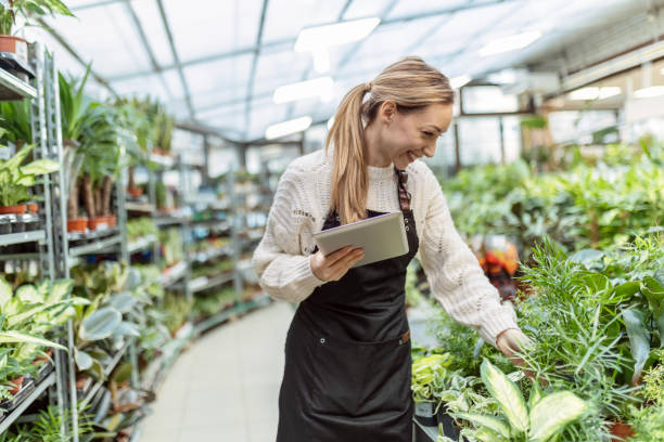 istock Young woman working at garden center checking inventory 1458237594