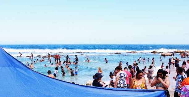 folla di persone sulla spiaggia di st james, vicino a muizenberg, città del capo, sud africa - women wading sun hat summer foto e immagini stock