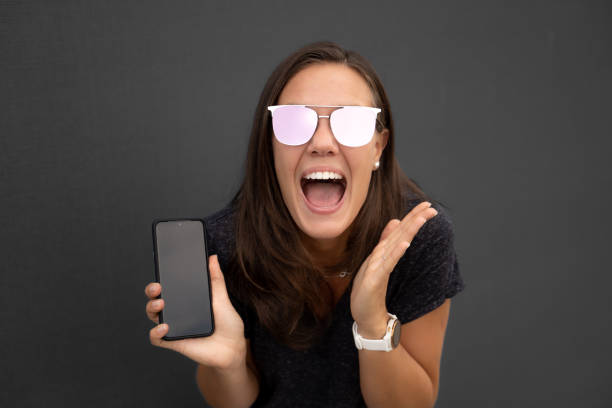 istock Excited young woman showing a smart phone screen 1458239793