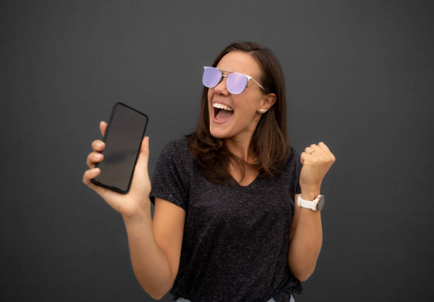 istock Excited young woman showing a smart phone screen 1458239820