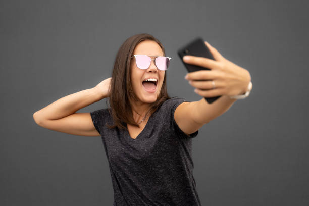 istock Happy young woman taking a selfie against a grey background 1458239854